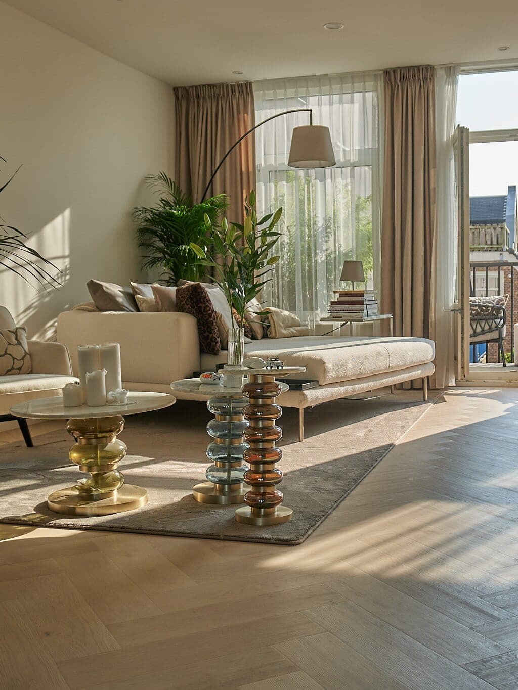 A finished living room handed back by L7M, oak herringbone floor, morning sun, balcony beyond