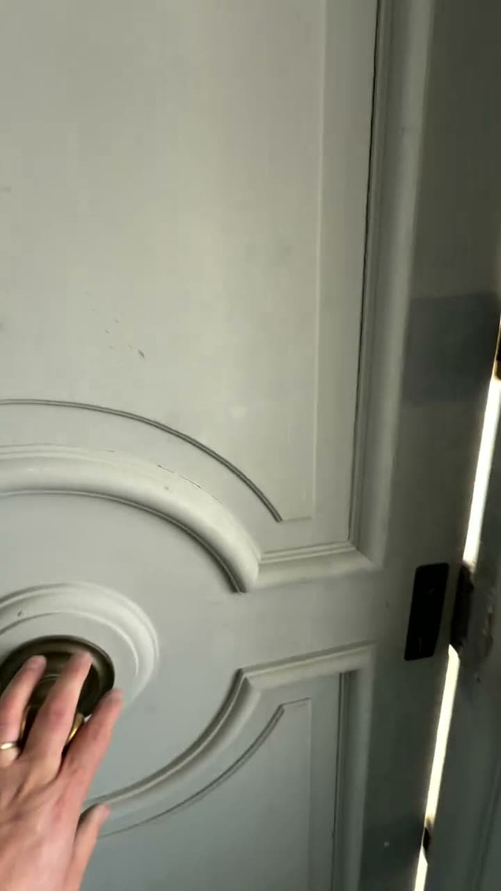 A hand pushing open an original panelled door, its mouldings and brass knob intact