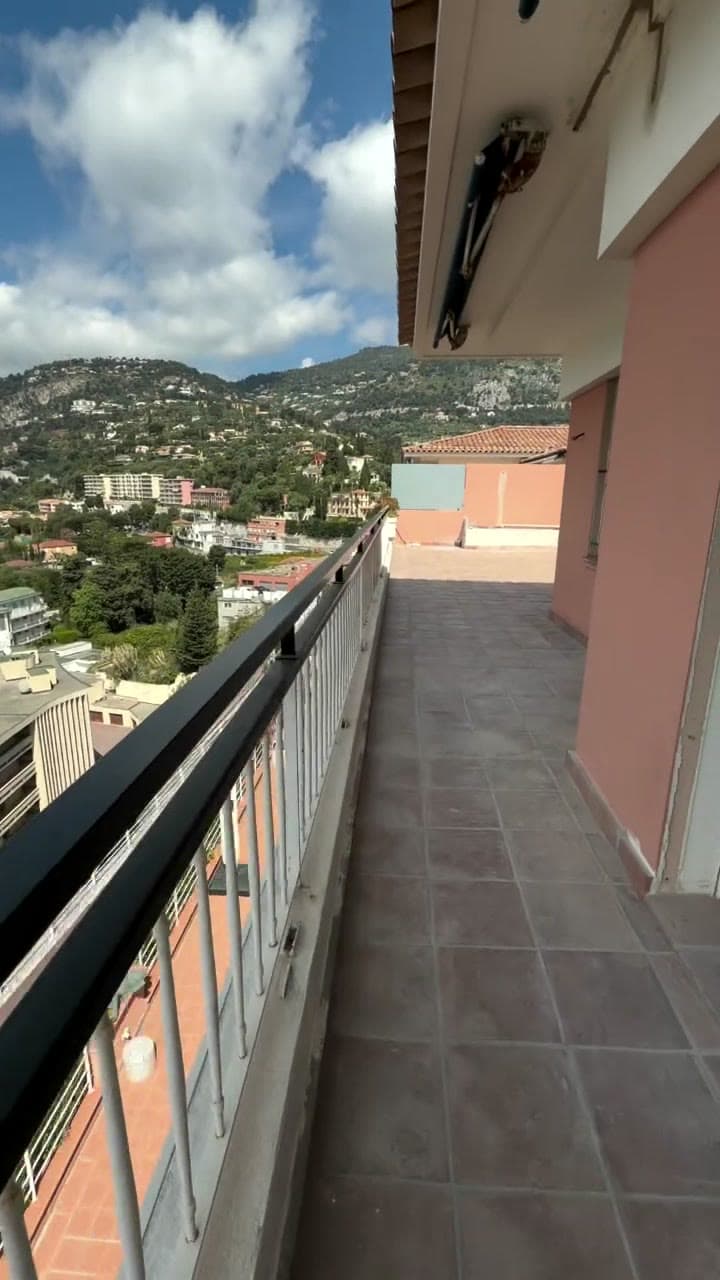 A long tiled terrace running along a hillside apartment, the town and hills beyond
